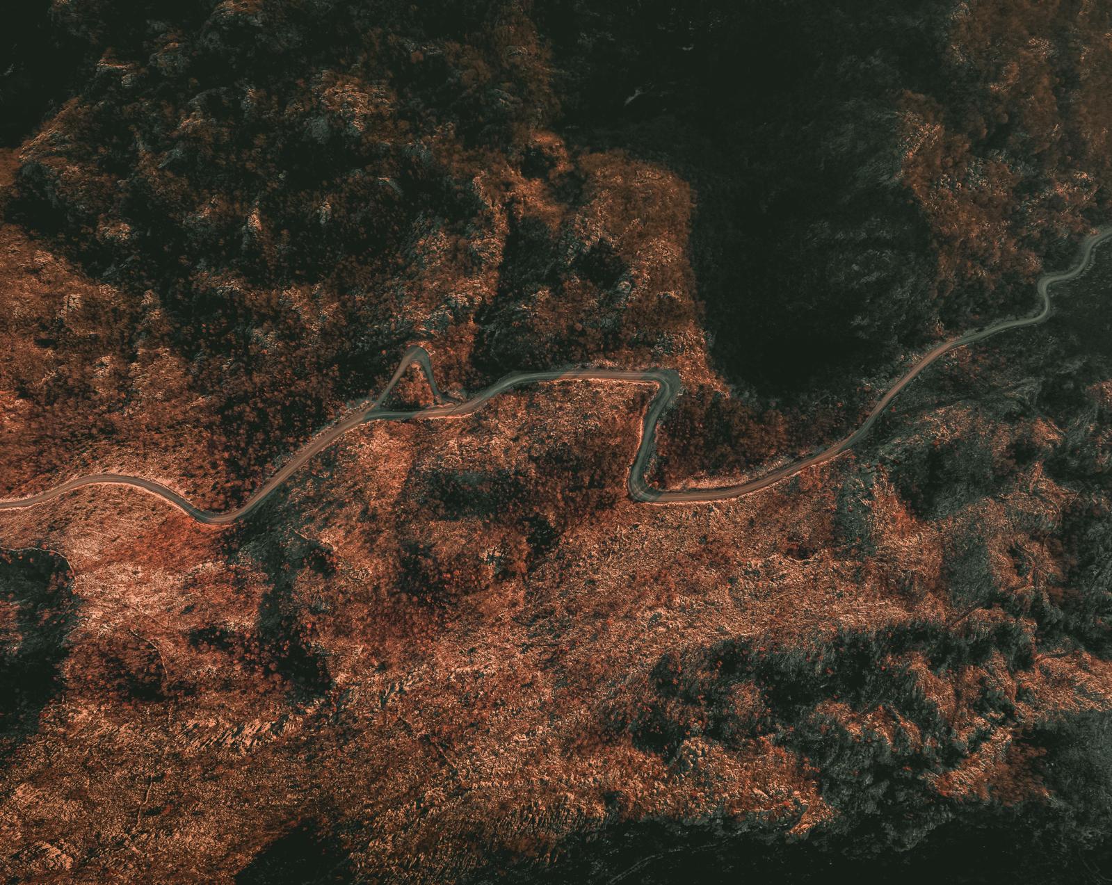 Aerial satellite view of terrain crossed by a winding road.